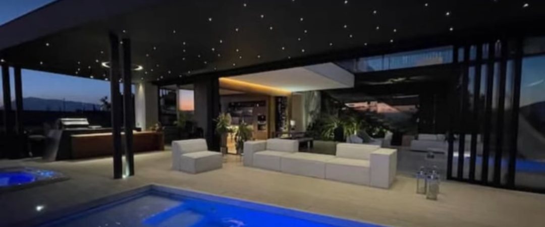 Sala exterior con cielo de estrellas y piscina iluminada